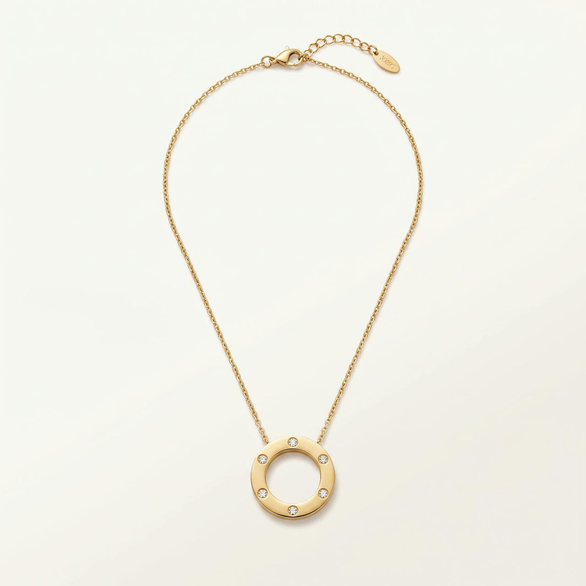 Collier doré pendentif cercle poli serti de quelques pierres sur fond ivoire