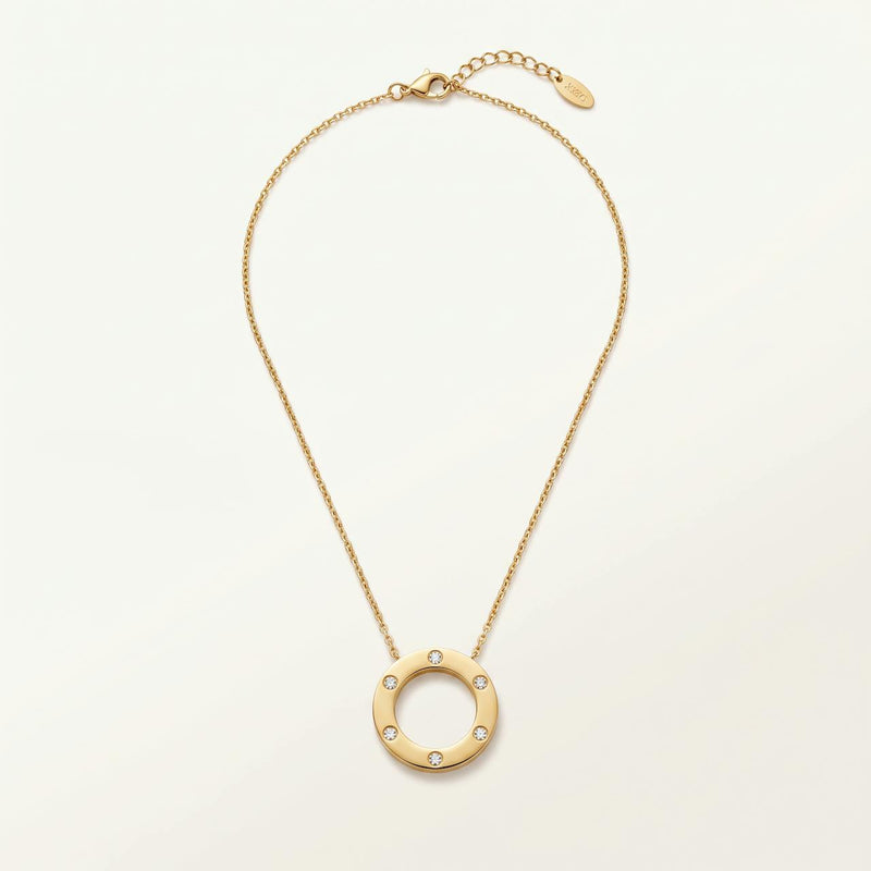 Collier doré pendentif cercle poli serti de quelques pierres sur fond ivoire
