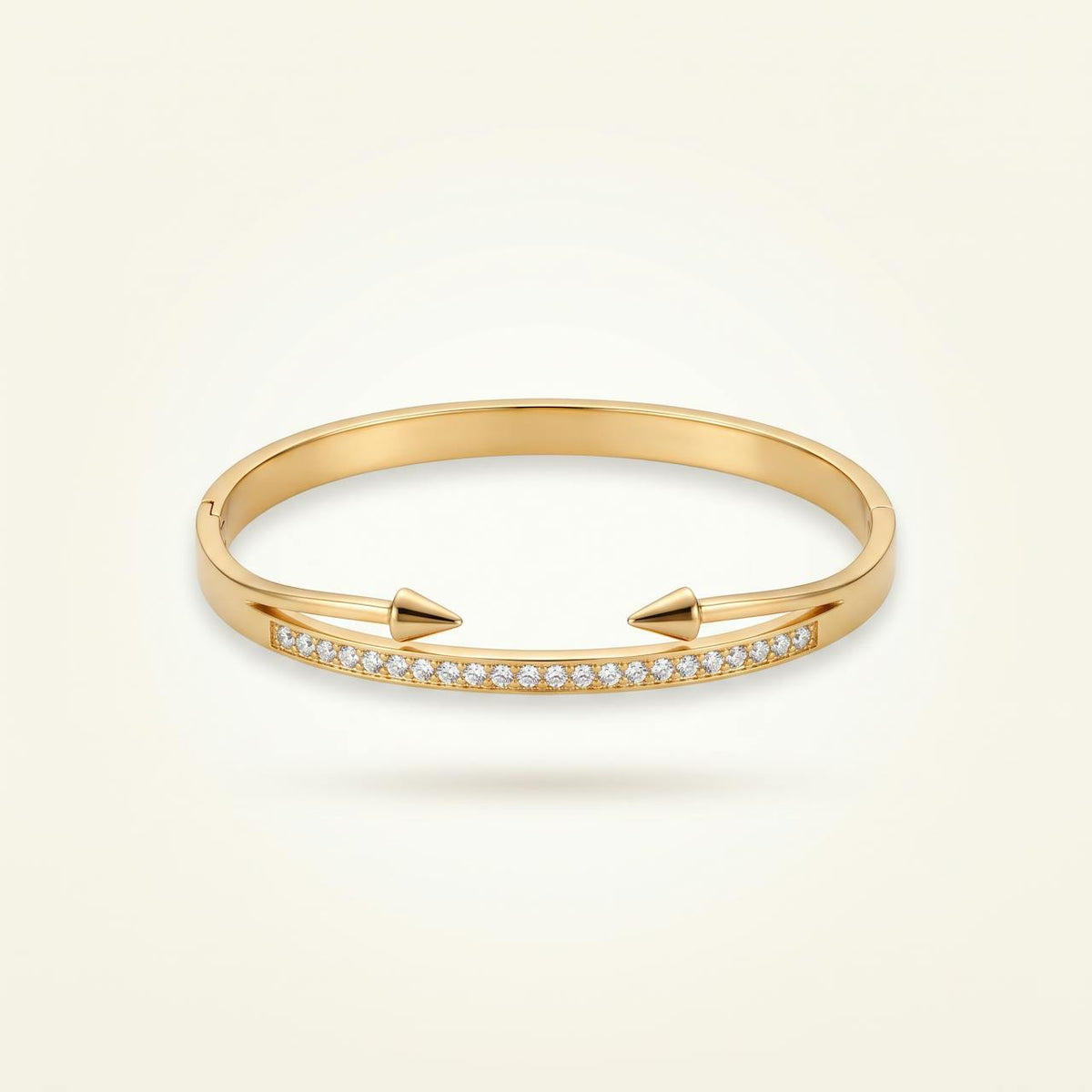 Bracelet jonc doré à pointes avec ligne de pierres sur fond ivoire