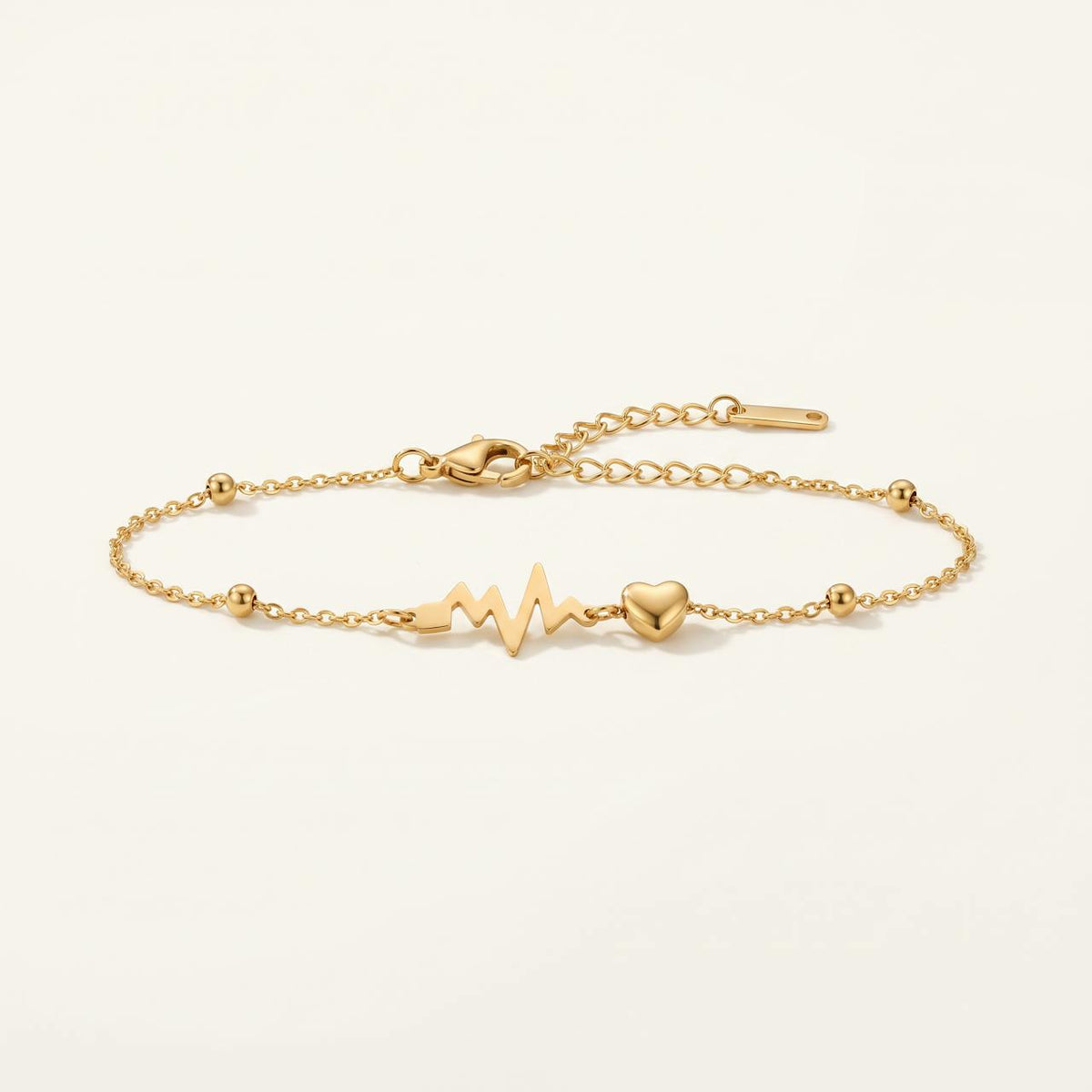 Bracelet doré motif battement de coeur et petit coeur sur fond ivoire